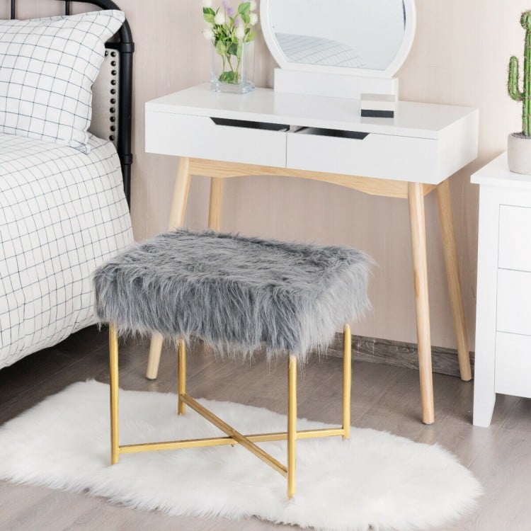 Gray faux fur ottoman stool with golden metal legs, perfect for bedroom or living room decor and compact spaces.