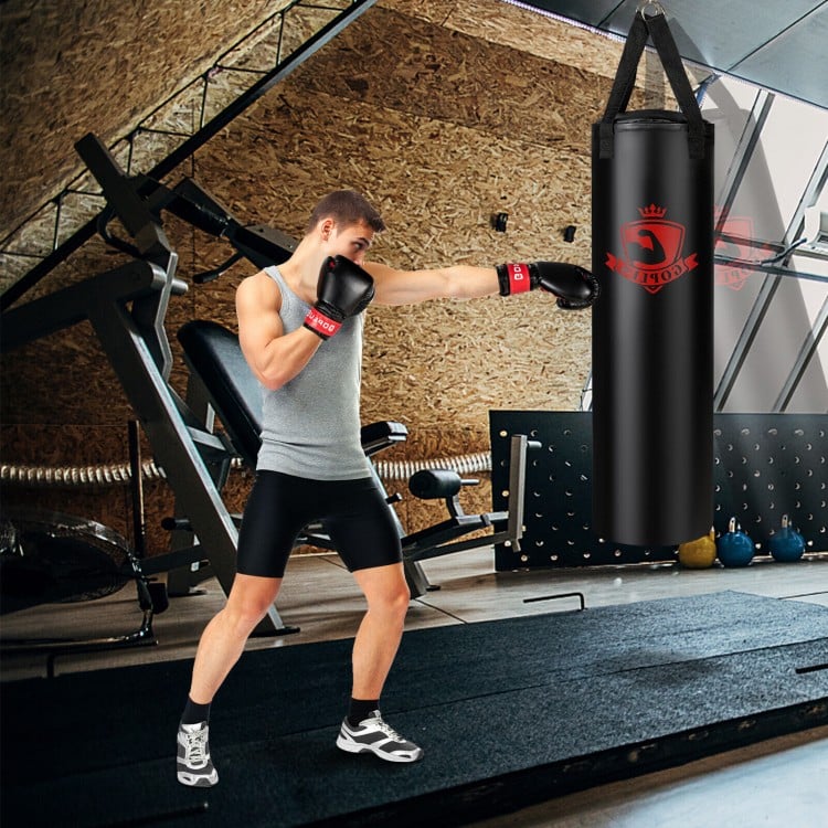 Boxer in training stance striking a hanging 63 lbs punching bag set, featuring durable PVC leather for effective.