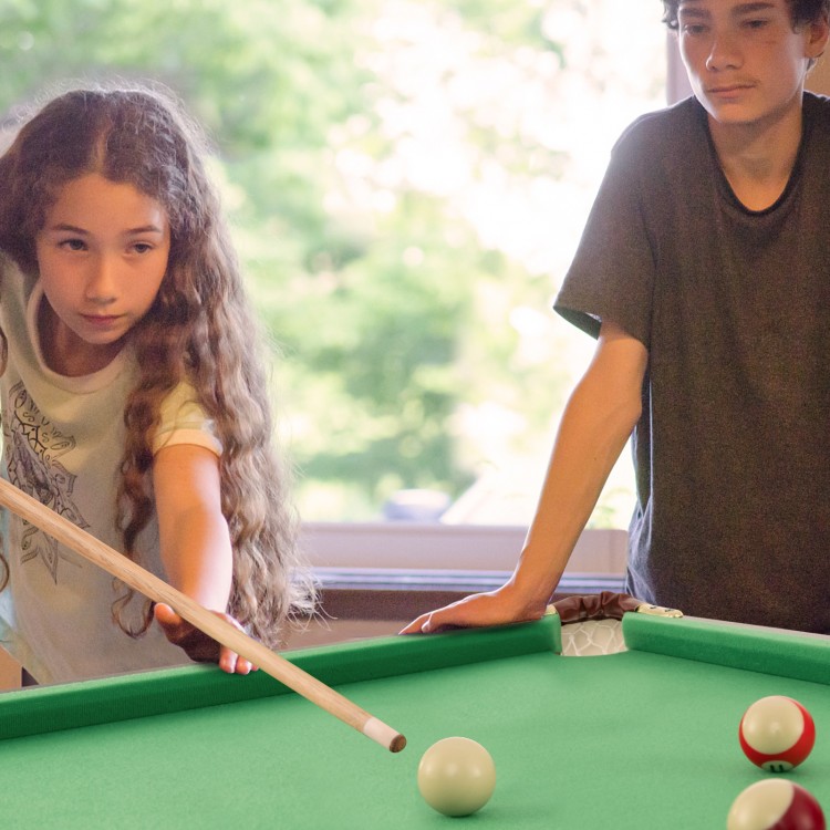 Kids playing on a 47-inch green folding billiard table, enhancing hand-eye coordination with cues and accessories.