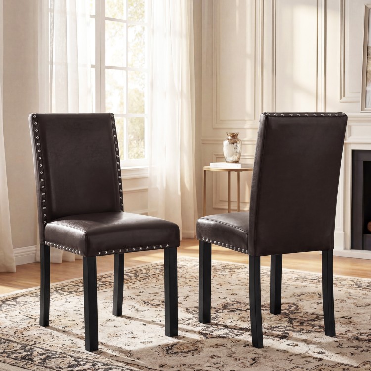 Set of two faux leather dining chairs with nailhead accents, curved backs, and solid wood legs for versatile dining use.