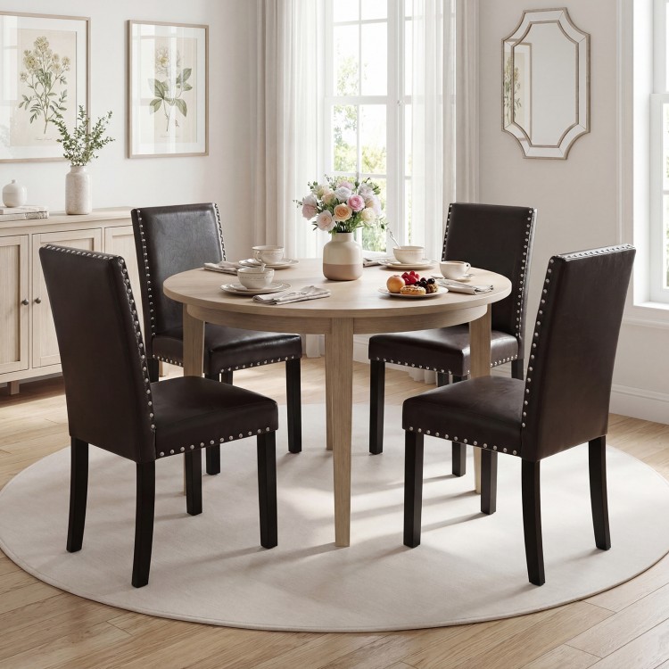 Faux leather upholstered dining chairs with solid wood legs and nailhead accents, perfect for kitchen or dining areas.
