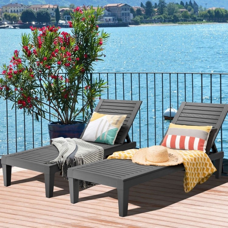 Set of 2 black outdoor chaise lounge chairs arranged by the poolside, perfect for stylish outdoor relaxation.