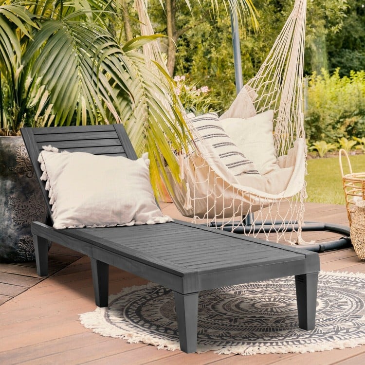 Black outdoor chaise lounge chair placed in a serene garden setting, ideal for backyard relaxation and easy transport.