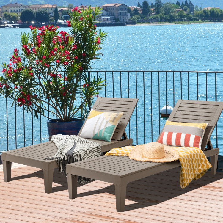 Two brown outdoor chaise lounge chairs on a deck by the water, ideal for garden, patio, or poolside relaxation.