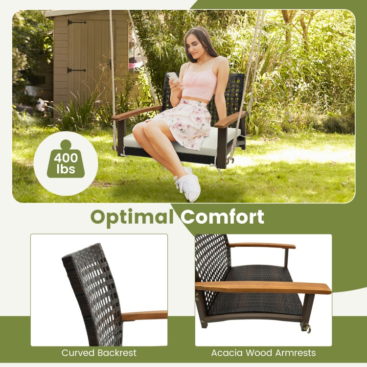 Single rattan porch swing with acacia wood armrests and cushion, designed for outdoor comfort, holds up to 400 lbs.