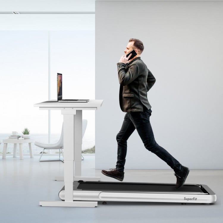 Folding treadmill in silver with remote control, used as an under-desk running machine for convenient exercise while.