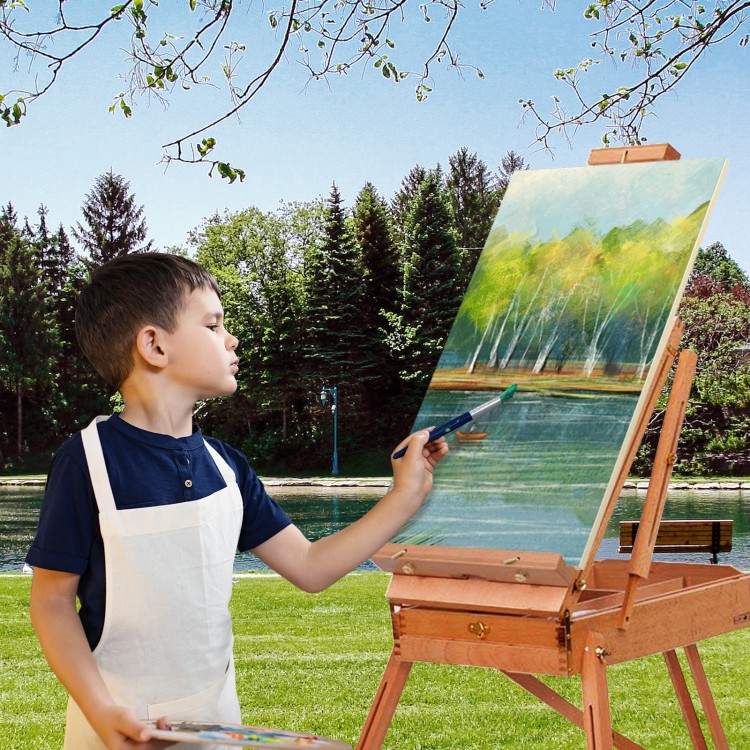 Young artist using a Tripod Folding French Wooden Easel with Sketch Box outdoors, perfect for painting and drawing.