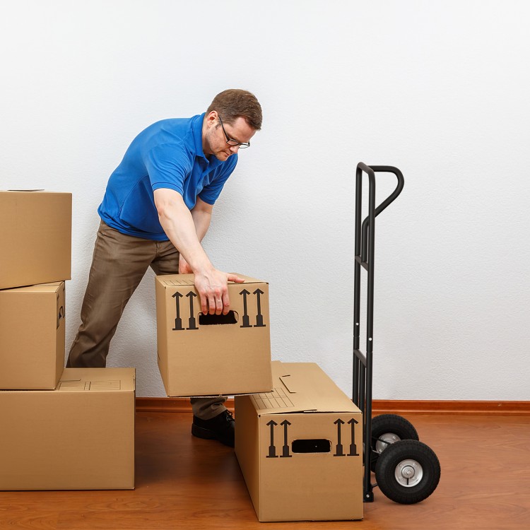 P-handle hand truck with foldable load plate, shown in use for moving boxes, ideal for warehouse and garage tasks.