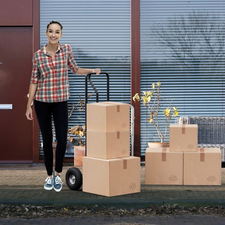P-handle hand truck with foldable load plate, ideal for package delivery and moving, shown with boxes outdoors.