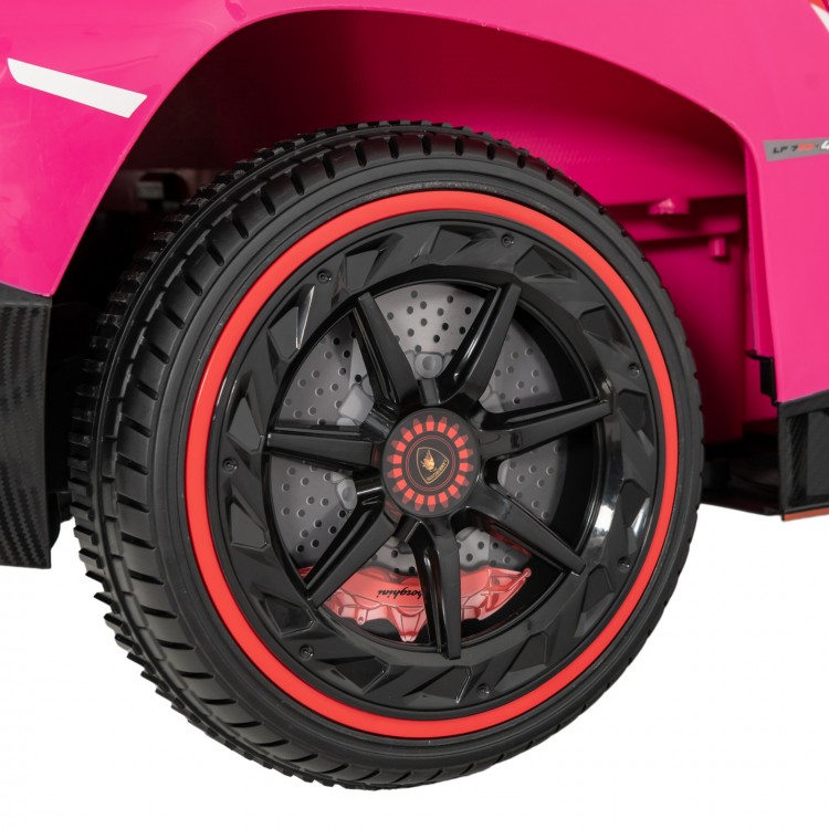 Close-up of the black wheel with red accents on the pink 12V Lamborghini kids ride-on sports car for fun outdoor.