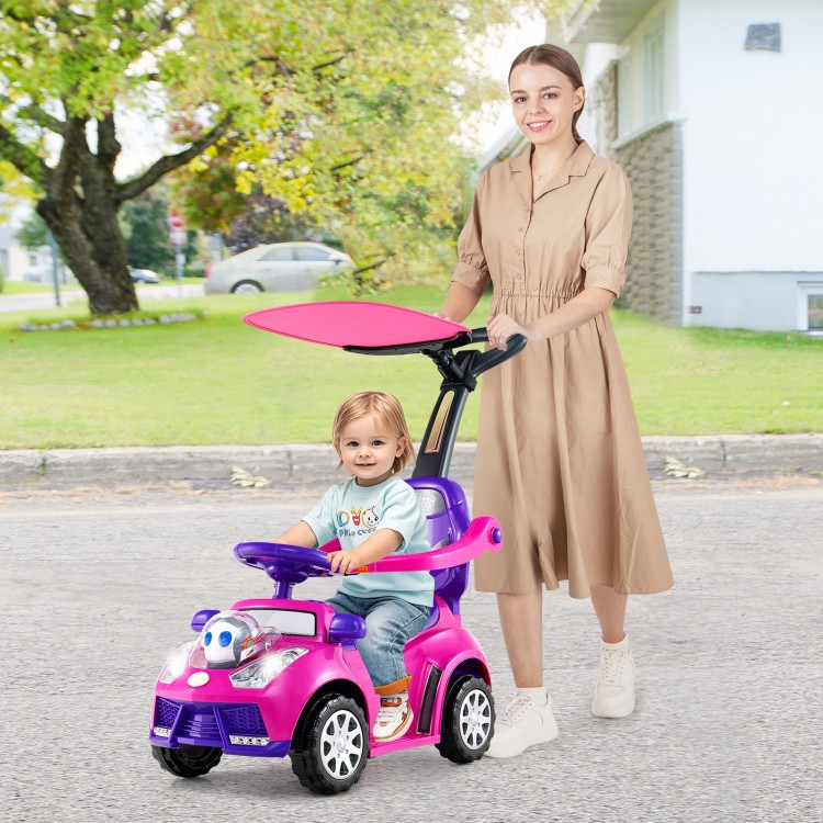Toddler riding in a pink 3-in-1 push car with adjustable canopy, guided by a parent in a park setting.