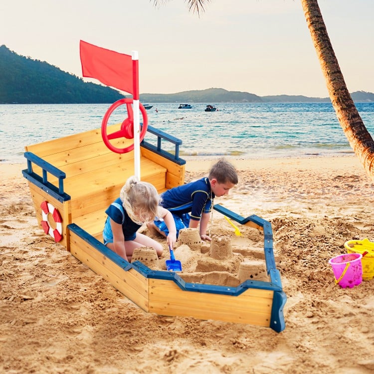 Kids playing in a wooden pirate boat sandbox, featuring lifebuoy and rudder, perfect for outdoor fun and creativity.