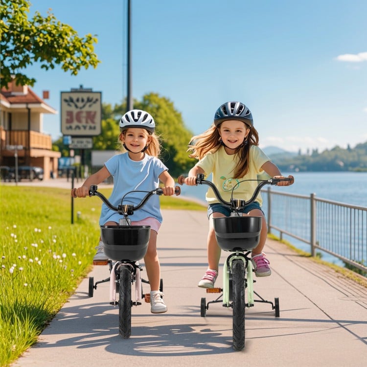 Two girls riding 14-inch kids bikes with training wheels along a scenic path by the water, promoting outdoor fun and.