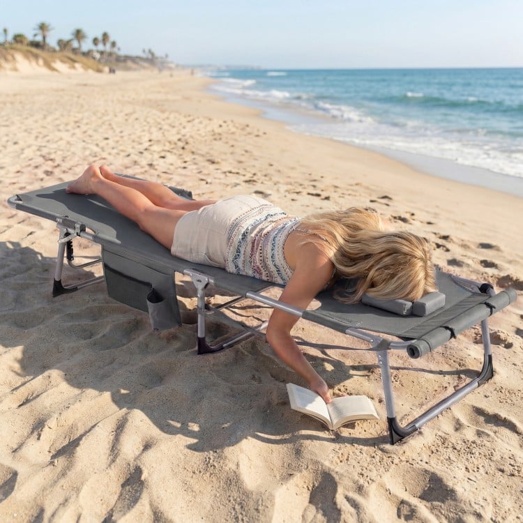 Portable gray tanning chair with face hole and arm openings, perfect for sunbathing at the beach or poolside.