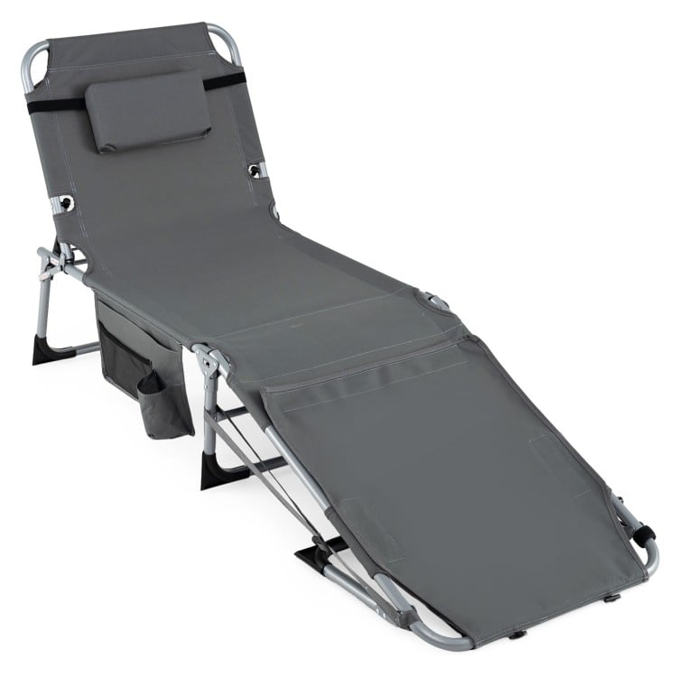 Portable gray tanning chair with face hole, adjustable backrest, and side pocket for sunbathing by the pool or beach.