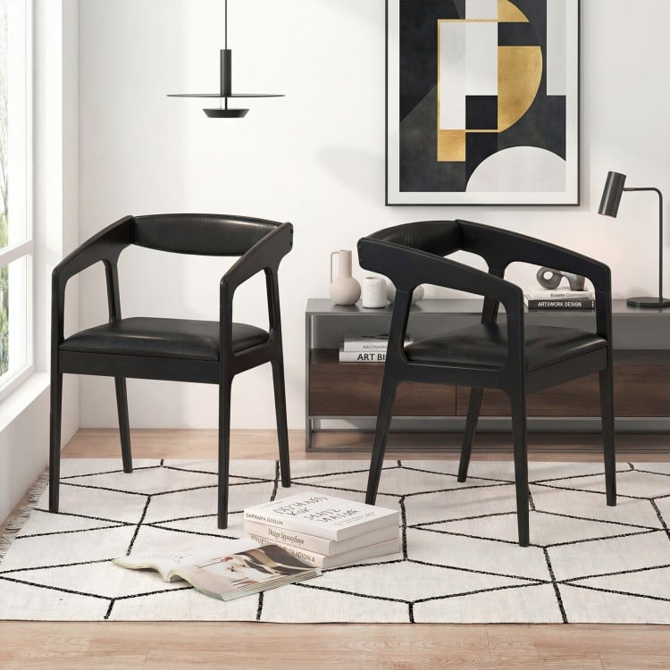Set of 2 black upholstered armchairs with ergonomic backrests and padded seats, ideal for dining or relaxing.