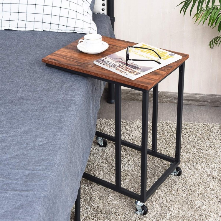 Mobile side table with a brown wood top and black metal frame, ideal for use beside a bed or sofa.
