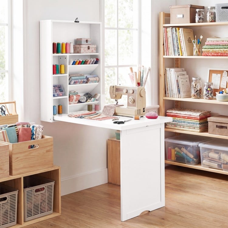 Wall-mounted fold-out convertible desk in white with ample storage, ideal for organizing craft supplies and workspace.