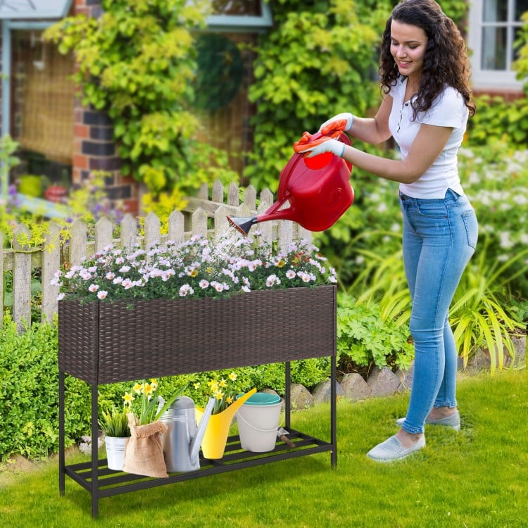 Wicker raised garden bed with storage shelf, featuring drainage gaps, ideal for growing flowers and herbs in any garden.