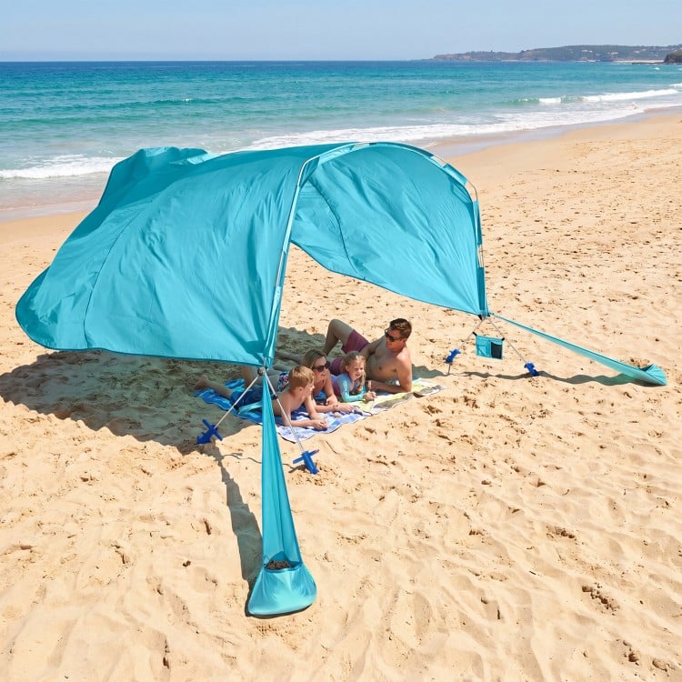 Portable blue beach tent providing 137 sq.ft shade for 6-8 people, ideal for family picnics by the ocean.