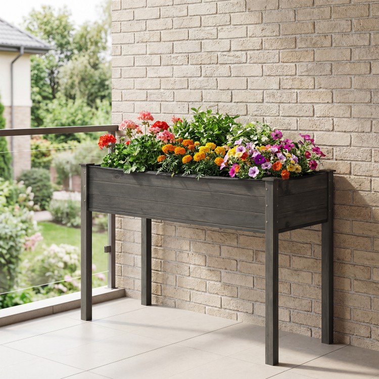 Elevated gray wooden vegetable planter with vibrant flowers, perfect for gardens and patios.