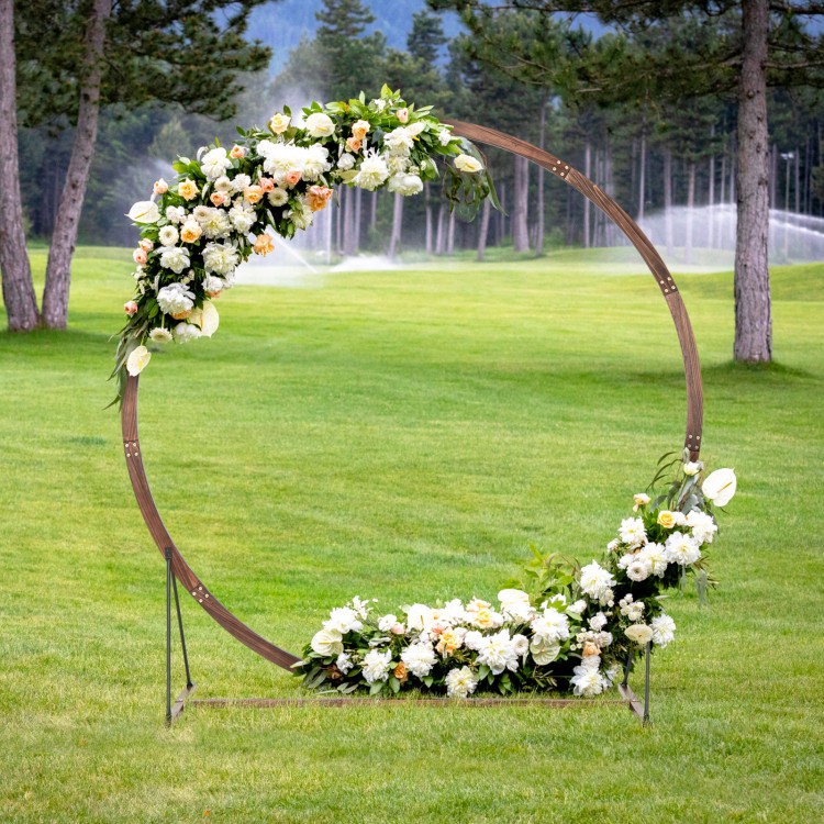 Wooden wedding arch in round shape, crafted from natural fir wood, adorned with white flowers for outdoor ceremonies.