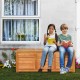 Acacia wood storage bench box with children reading, offering 46-gallon capacity for outdoor patio or garden use.