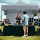 Pop-up canopy tent with gray fabric, removable sidewalls, and a wheeled bag, ideal for outdoor events and markets.