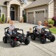 Two kids driving a dark gray 12V battery-powered ride-on tractor with a detachable trailer for outdoor fun.