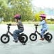 Kids riding 12-inch black bikes with removable training wheels, adjustable seats, and safety features for ages 3-8.