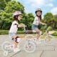 Two children riding a pink 12-inch kids bike with training wheels, designed for ages 3-8, featuring adjustable seat and.