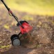 14-inch electric tiller with 10-amp motor, cultivating soil in a garden, ideal for small to medium-sized spaces.