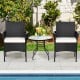 Two patio wicker chairs with cozy seat cushions beside a glass table, perfect for outdoor relaxation by the poolside.