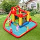 Inflatable water slide bounce house with climbing wall, splash pool, and water cannon for summer fun in the backyard.