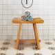 Teak shower bench with curved seat, featuring solid construction and water resistance, ideal for shaving legs or as a.