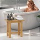 Teak shower bench with towels and toiletries, ideal for shaving legs in a stylish bathroom setting.