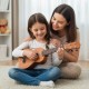 21-inch soprano mahogany ukulele set being played by a girl, featuring nylon strings and an adjustable strap for.