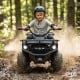 Child riding the 24V Electric Ride On Quad in black, featuring LED headlights and wear-resistant wheels for outdoor fun.