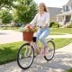 Pink 24-inch beach cruiser bike with woven basket and cup holder, perfect for leisurely rides and flower deliveries.