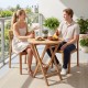 Round 24" solid teak outdoor folding bistro table with footrest, perfect for small spaces on patios or balconies.