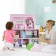 Child playing with a 28-inch pink dollhouse, featuring 5 rooms and colorful furniture, perfect for interactive fun.