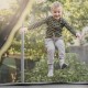 Child jumping on a trampoline with a weather-resistant safety enclosure net for secure and enjoyable play.