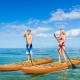 Two people paddle on inflatable stand-up paddle boards in clear water, ideal for water sports and summer fun.
