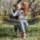 Kids enjoying the Saucer Tree Swing in army green, featuring adjustable height and comfortable foam handles for safety.