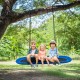 Oval 60-inch blue and black saucer swing with three children enjoying outdoor play, promoting friendship and.