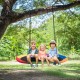 Oval 60-inch multicolor saucer swing with three children enjoying outdoor play, adjustable height for various spaces.