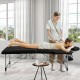 Portable adjustable massage bed in black with headrest and armrests, ideal for spa and facial treatments.