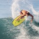 A surfer riding a wave on a bright yellow Super Lightweight Bodyboard-M, designed for durability and buoyancy.