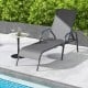 Dark gray outdoor patio lounge chair with adjustable recline, set by the poolside for relaxation and comfort.