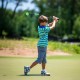Child practicing golf swing with a 31.5-inch green swing trainer aid on a sunny course, enhancing grip and balance.